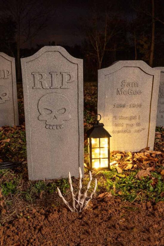 diy halloween tombstones on the ground in garden with a lantern